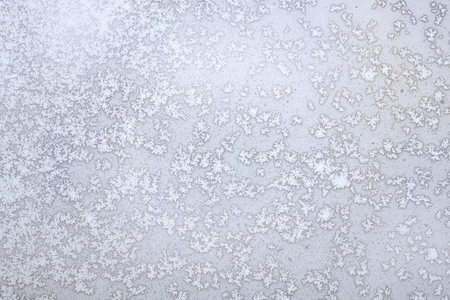 Natural background with white frost on the frozen window glass in the cold winter day front view closeupの写真素材