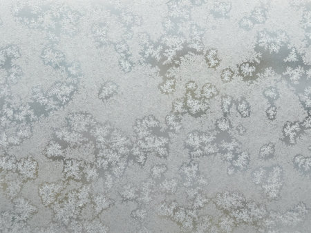 Natural background with white melting frost on the frozen window glass in the cold winter day front view closeupの写真素材