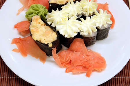 Still-life with appetizing sushi pieces on the white plate on brown wicker straw mat top view closeupの写真素材