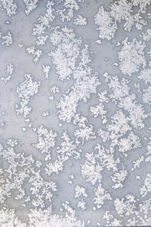 White melting frost on the frozen window glass in the cold winter day as natural background front view vertical closeupの写真素材