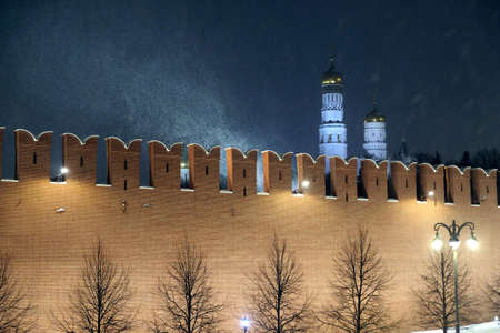 The Kremlin Wall and cathedrals after it in Moscow Russia with holiday lighting during cold Russian winter blizzard on nightの写真素材