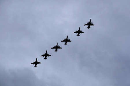 Contours of six Russian military tactical frontline bombers SU-25 Frogfoot fast flying in gloomy cloudy skyの写真素材
