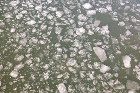 Broken spring ice floes floating on the river aerial top view from droneの写真素材