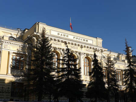 Facade of building of Central Bank of Russia in Moscow with state flag on the top of the building under clear blue sky on sunny dayの写真素材