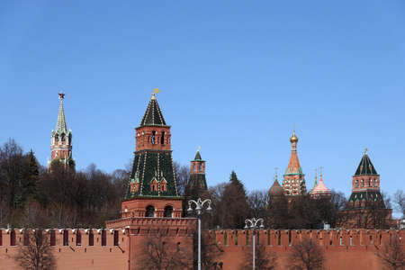 Towers of Moscow Kremlin behind wide red brick wall in bright spring sunny day under cloudless blue skyの写真素材