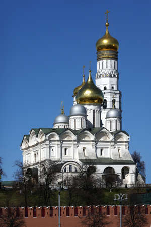 Ivan the Great Bell Tower with golden cupolas behind the Kremlin wall view from embankment of the Moscow riverの写真素材