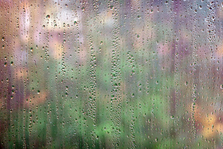 Motley colorful blur autumn background front view through rain droplets on window glass closeupの写真素材
