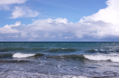 Seascape with stormy sea waves with foam under heavy cumulonimbus on the sky till horizonの写真素材