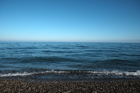 Calm landscape with small waves on water surface to skyline under clear cloudless sky horizontal viewの写真素材