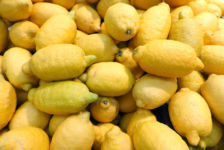 Crop of many ripe yellow lemons fruits in the showcase as background top view close upの写真素材