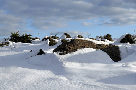 Nordic winter landscape with hills and big stones on clean sparkling snowy surface on bright sunny dayの写真素材