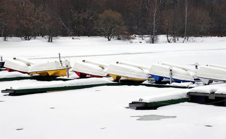WInter landscape with many overturned boats in the snow on a dock on a frozen river in no seasonの写真素材