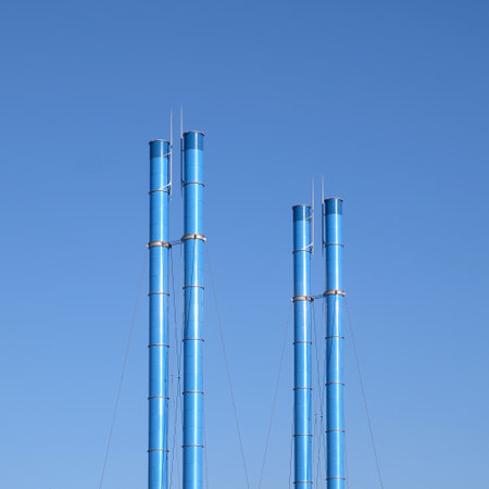 Four painted blue pipes on clear blue sky with no cloudsの写真素材