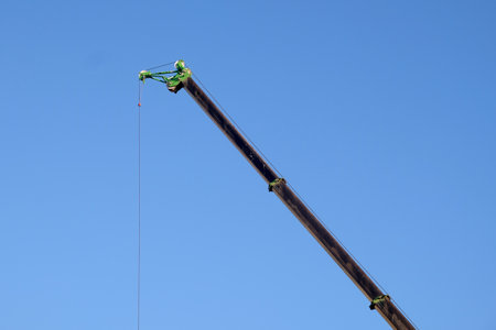 Long boom crane manipulator high in the blue cloudless skyの写真素材