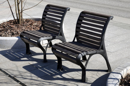 Two stylish street chairs as benches on the stone pavement in the city side view close upの写真素材