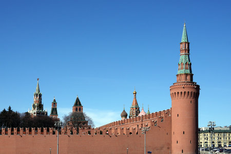 Long red brick Kremlin wall with towers with spires and stars under clear blue skyの写真素材