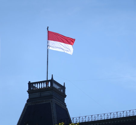 Austrian flag fluttering on the top of house roof on sunny cloudless dayの写真素材