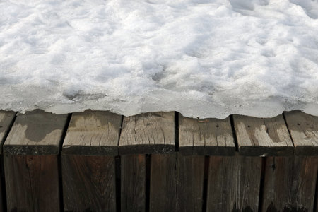 Melting on spring snow on the old brown wooden boards surface outdoors front view close upの写真素材