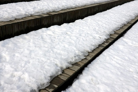 Melting on spring snow on the different surfaces of old brown wooden boards surface outdoors side view close upの写真素材