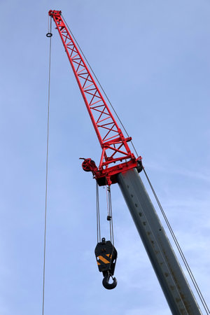 Big construction arm crane with heavy hook on clear blue sky closeup view vertical photoの写真素材