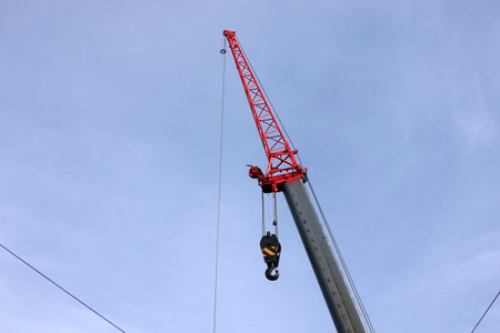 Big construction arm crane with heavy hook on metal cable on clear blue skyの写真素材