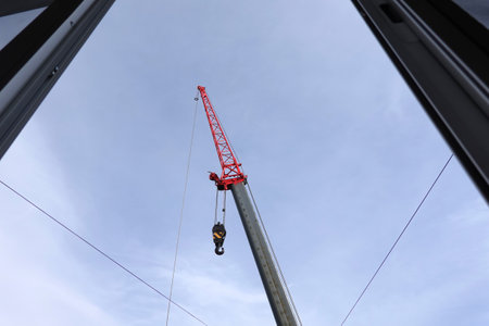 Big construction arm crane with heavy hook on metal cable view from opened windowの写真素材