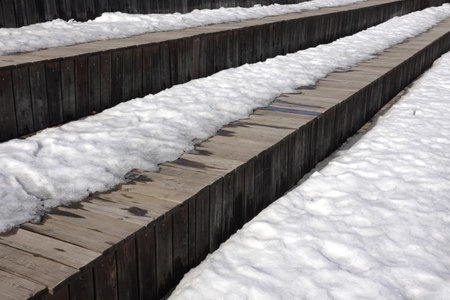 Melting on spring snow on the different surfaces of old brown wooden boards surface outdoors side view close upの写真素材