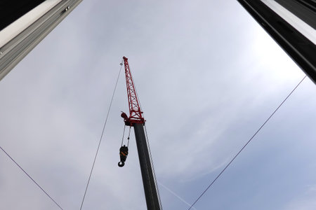 Big construction arm crane with heavy hook on metal cable view from opened windowの写真素材
