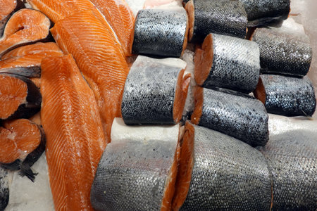 Lot of fresh chilled salmon steaks and red fish pieces with scales lies in shop front in sea food store top view close upの写真素材