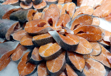 Lot of fresh red chilled salmon steaks lies on the ice in showcase in sea food store top view close upの写真素材