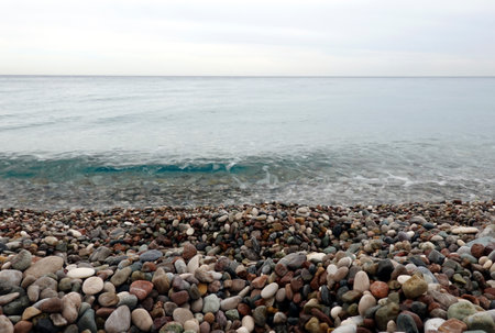 Beach with small smooth pebble and clean calm transparent sea till skylineの写真素材