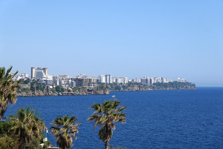 View in sunny day to the water area and the port of Antalya with boats and yachts in the sea near the old city from park with palmsの写真素材