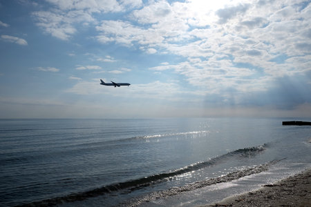 Landscape with calm sea to horizon and large passenger aircraft preparing to landingの写真素材