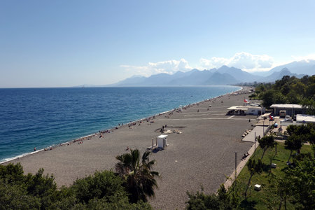 Sun, endless beach, cloudless sky, sea and far mountains in Antalya resortの写真素材