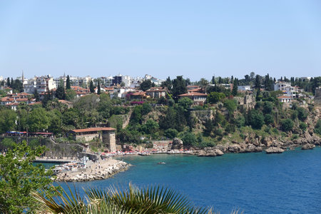 View to the azure sea water and the port dam of Antalya and the old city from park with palms in sunny cloudless dayの写真素材