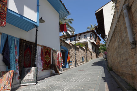 Going up on empty back street with handmade craft carpet shop in the tourist area in Antalya old city in heat dayの写真素材