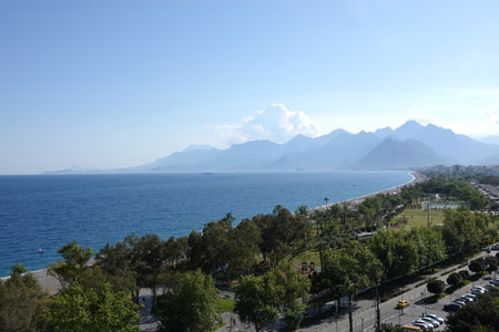 Landscape with logn beach and park, cloudless sky, sea and mountains at far in Antalya resort areaの写真素材