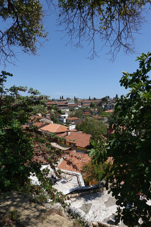 Nice view of the tiled roofs of dense standing houses of the Antalya old city through south vegetation on a hot sunny dayの写真素材