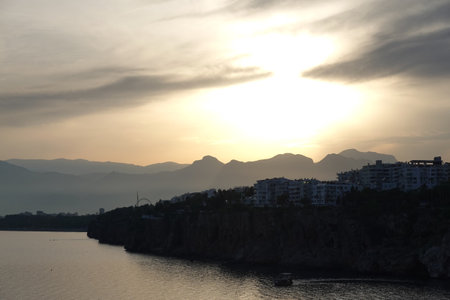Landscape with beautiful calm sunset with high mountains silhouettes covered with light haze on skyline and Antalya coastlineの写真素材
