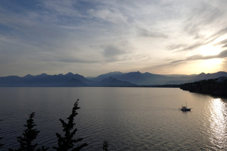 Landscape with beautiful calm sunset with high mountains silhouettes covered with light haze on skyline and Antalya coastlineの写真素材