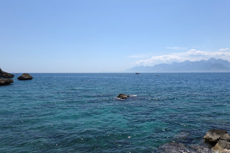Beautiful calm sea and high mountains in haze at far on skyline in sunny summer dayの写真素材