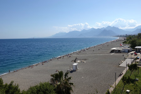Sun, endless beach, cloudless sky, sea and far mountains in Antalya resortの写真素材