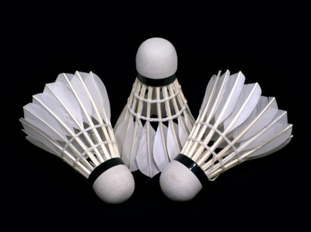 Three white badminton shuttlecocks from synthetic feathers isolated on black background indoor studio shot front view closeupの写真素材