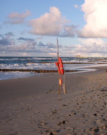 Life preserver on the stand on empty sandy beach near storming sea wavesの写真素材