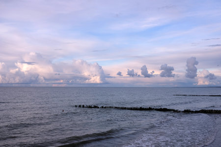 Seascape with sea sunset beginning and small waves continues till heavy colorful clouds on skylineの写真素材