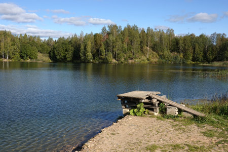 Countryside landscape with calm still lake and small bridge for jumping into water on frontの写真素材