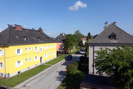 Quiet street with beautiful colorful houses and parked cars in small Austrian town on sunny dayの写真素材