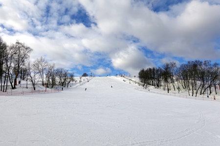 Ski slope front view with few ski riders skiing in the morning at ski resort with beautiful winter weatherの写真素材