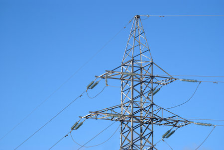 Top section of high-voltage power line metal prop on clear blue sky as backgroundの写真素材