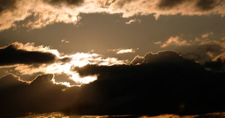 Beautiful sky panoramic landscape in golden colors with sun through cumulonimbus on sunsetの写真素材